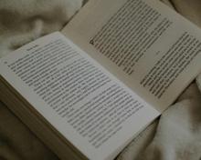 offenes Buch auf einer Bettdecke 