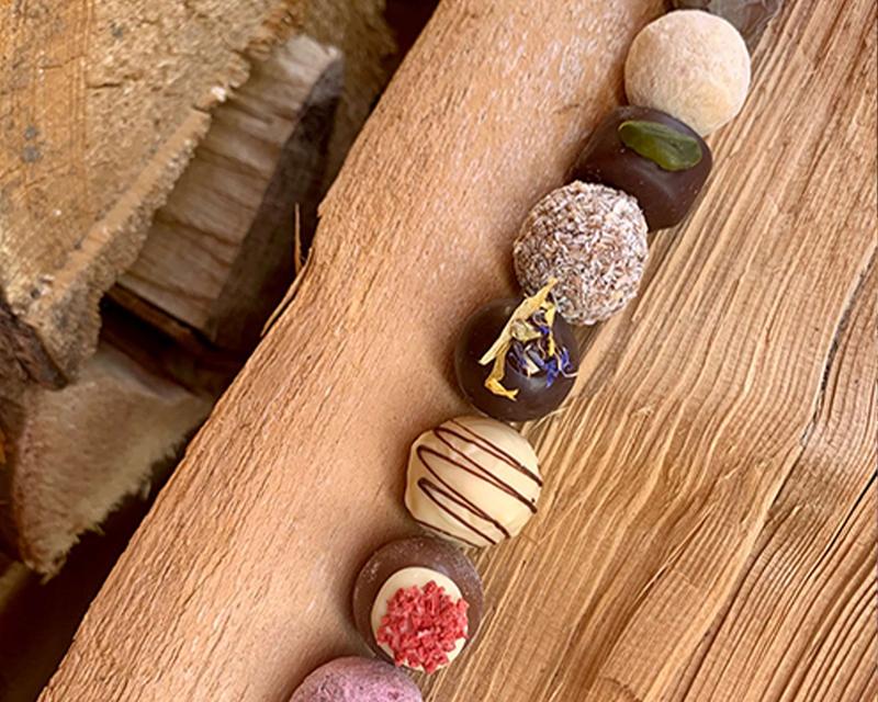 Verscheidenst Pralinen in einer Reihe auf einem Holzbrett