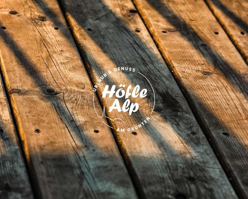 Nahaufnahme Holzterrasse mit dem Höfle Alp Logo
